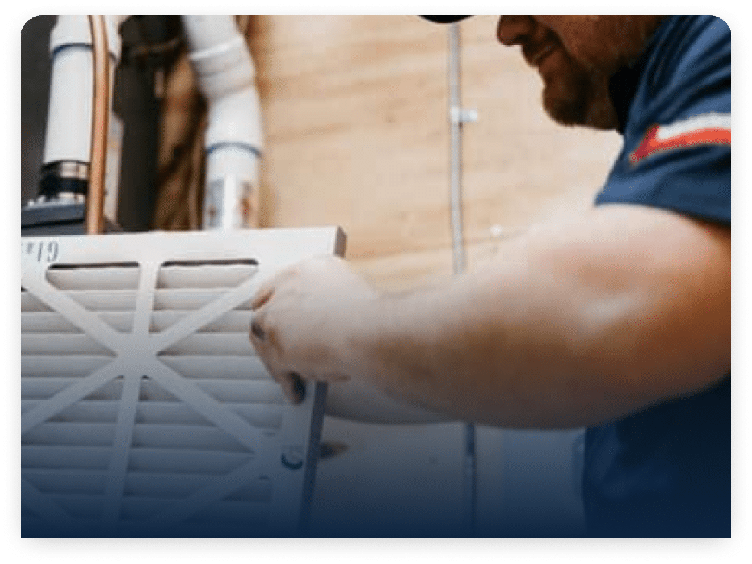 Homeowner sliding a clean pleated filter into a return air vent